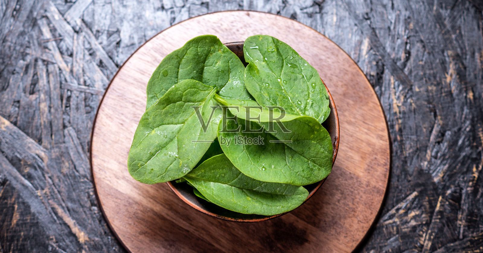 绿色的新鲜菠菜的叶子在一个盘子在一个深色的背景。健康的素食。俯视图照片摄影图片