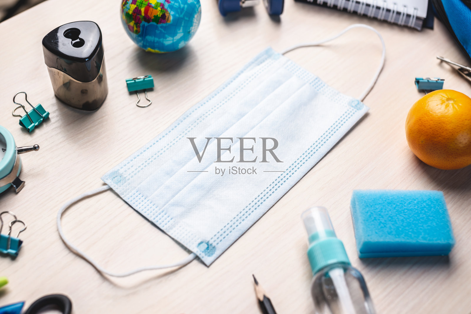 文具学校用品的桌子上有医用口罩。前视图。返校理念照片摄影图片