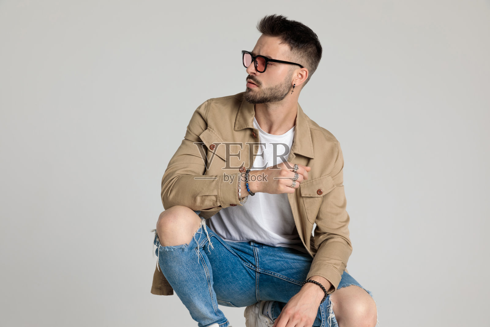 性感的年轻人穿着夹克,戴着眼镜,看向一边照片摄影图片