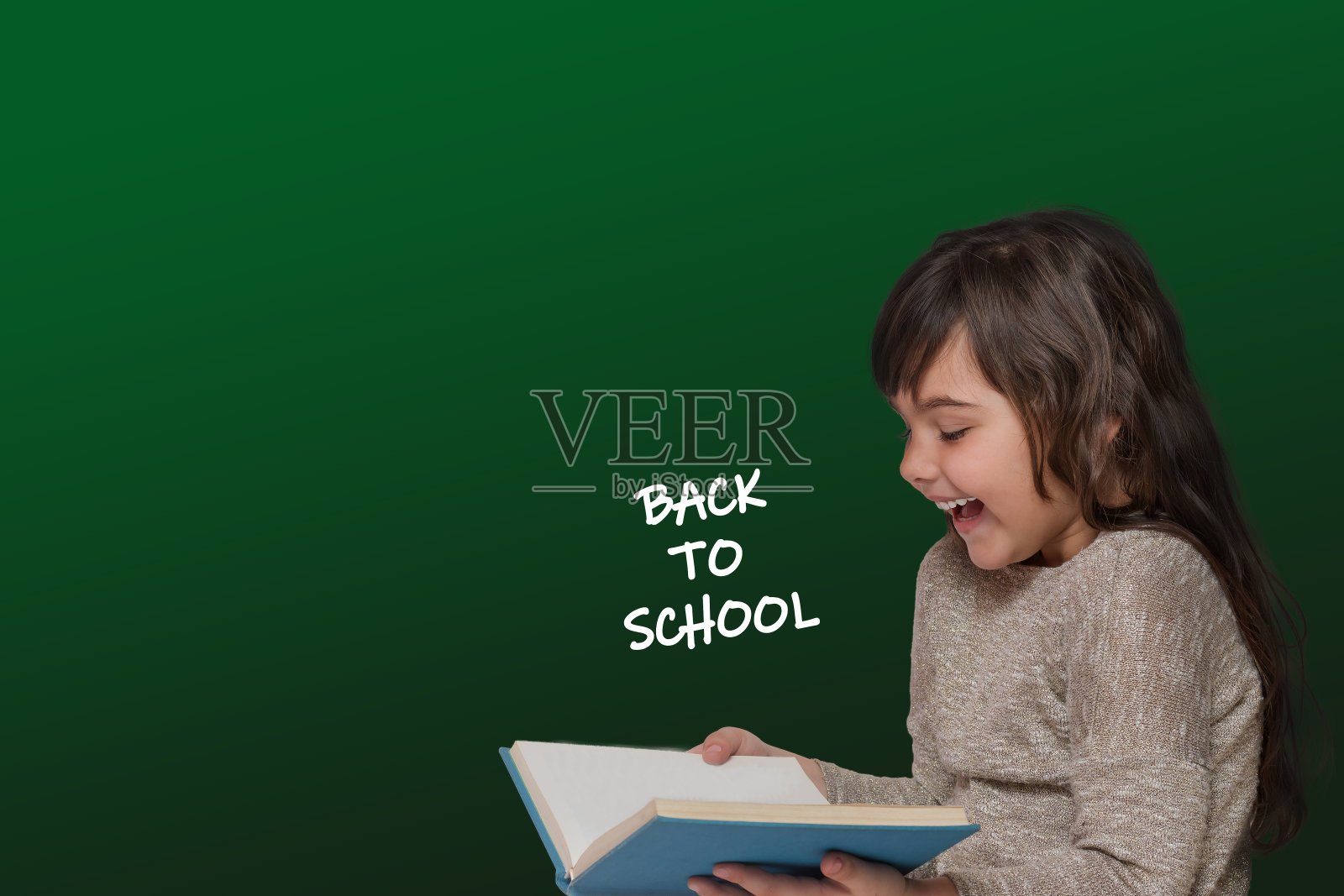 回到学校的概念显示笑可爱的晒黑小女孩拿着一本书照片摄影图片