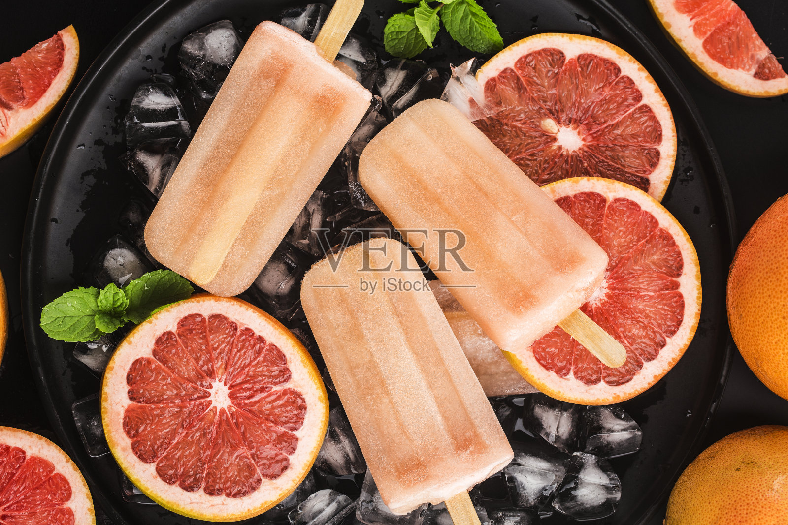 红葡萄柚自制冰棒加冰块。照片摄影图片