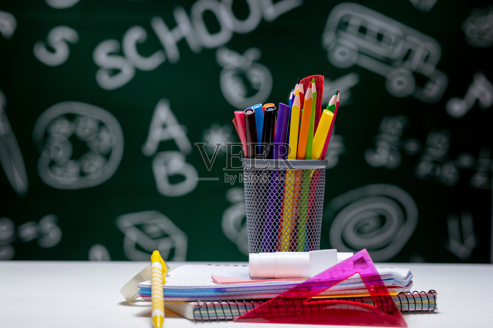 学校背景和文具配件。书、地球仪、铅笔和各种办公用品躺在绿色黑板背景的桌子上照片摄影图片