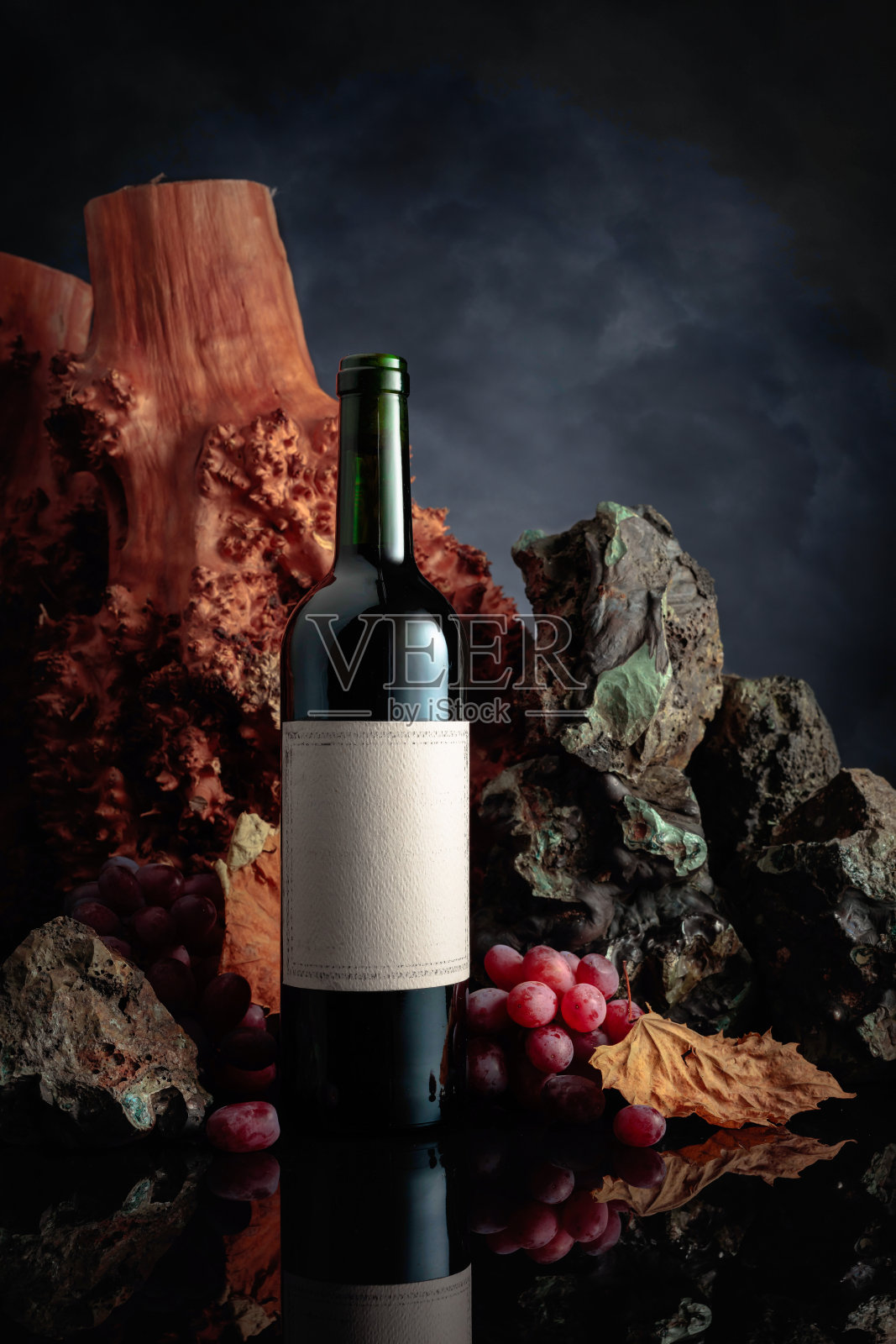 红酒和葡萄在黑色的反光背景上。空的旧标签。照片摄影图片