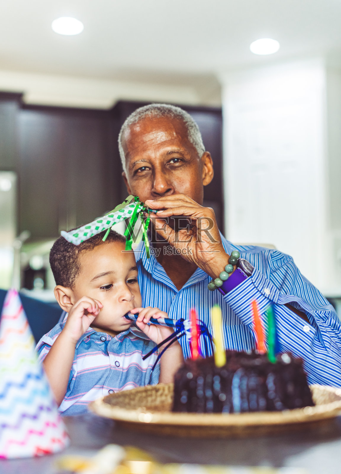 非裔美国人祖父和孙子在家庭生日庆典上吹响派对号角照片摄影图片