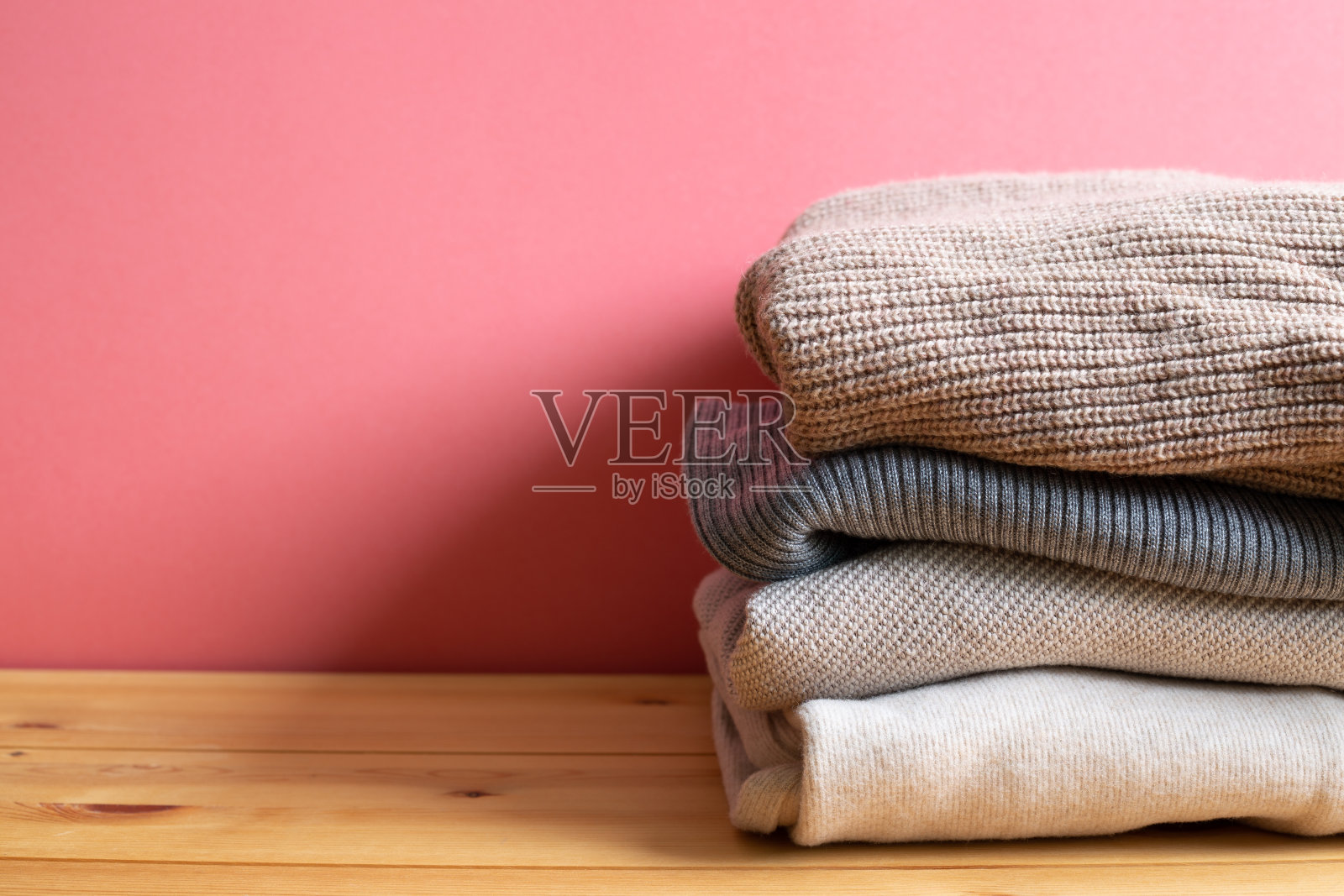 一堆暖和的毛衣衣服放在木桌上。秋冬概念。与复制空间照片摄影图片