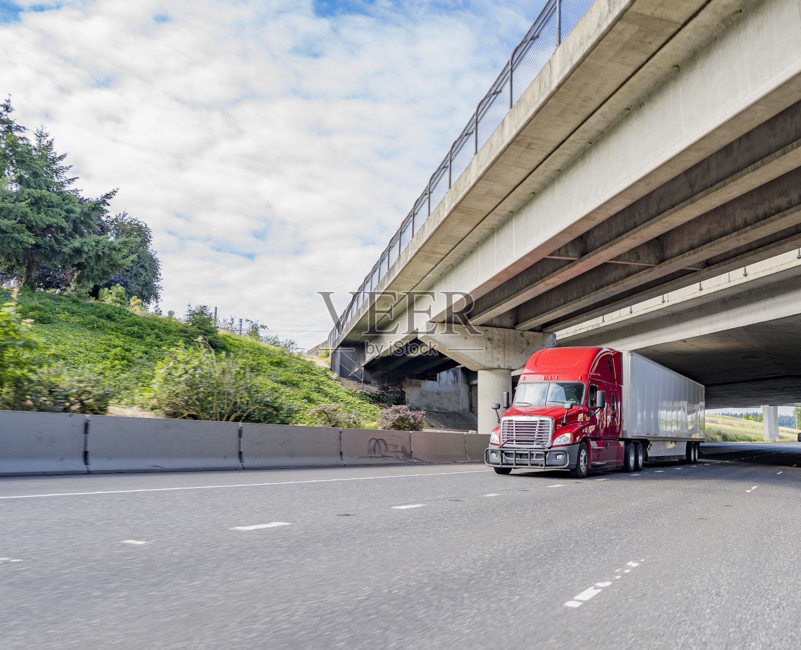 明亮的红色长途柴油大钻机半挂车与干式货车半挂车行驶在笔直的公路桥下照片摄影图片