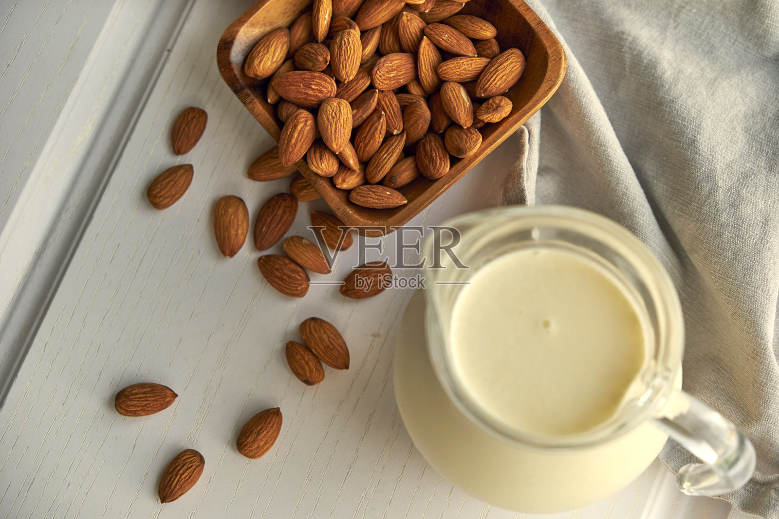 白色木桌上,杏仁牛奶和杏仁木碗照片摄影图片