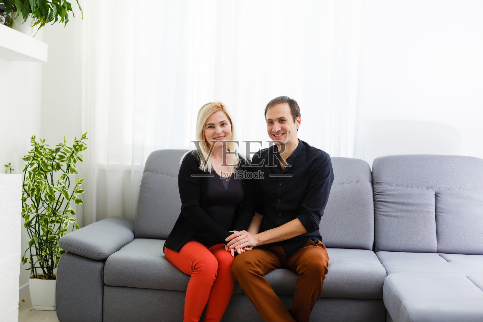 一对幸福的年轻情侣坐在心理治疗师的沙发上拥抱微笑。照片摄影图片