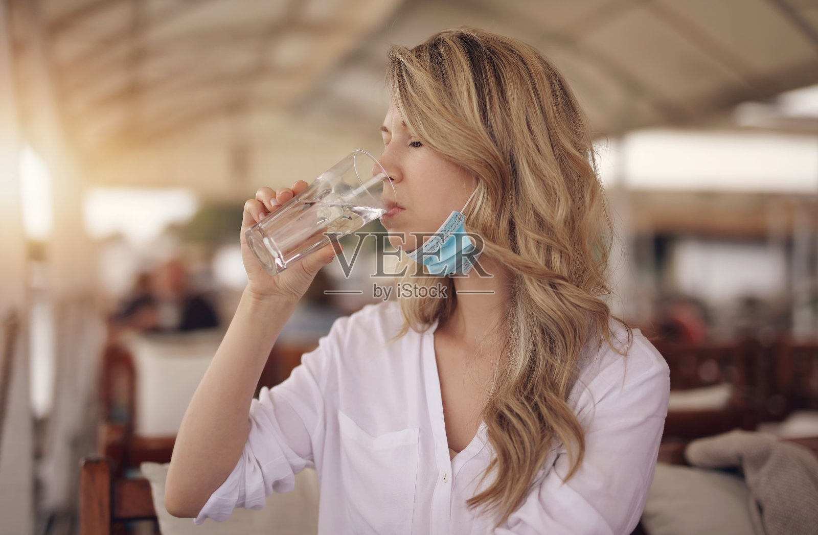 预防,防护。餐馆重新开业,妇女戴着防护口罩在餐馆饮水照片摄影图片