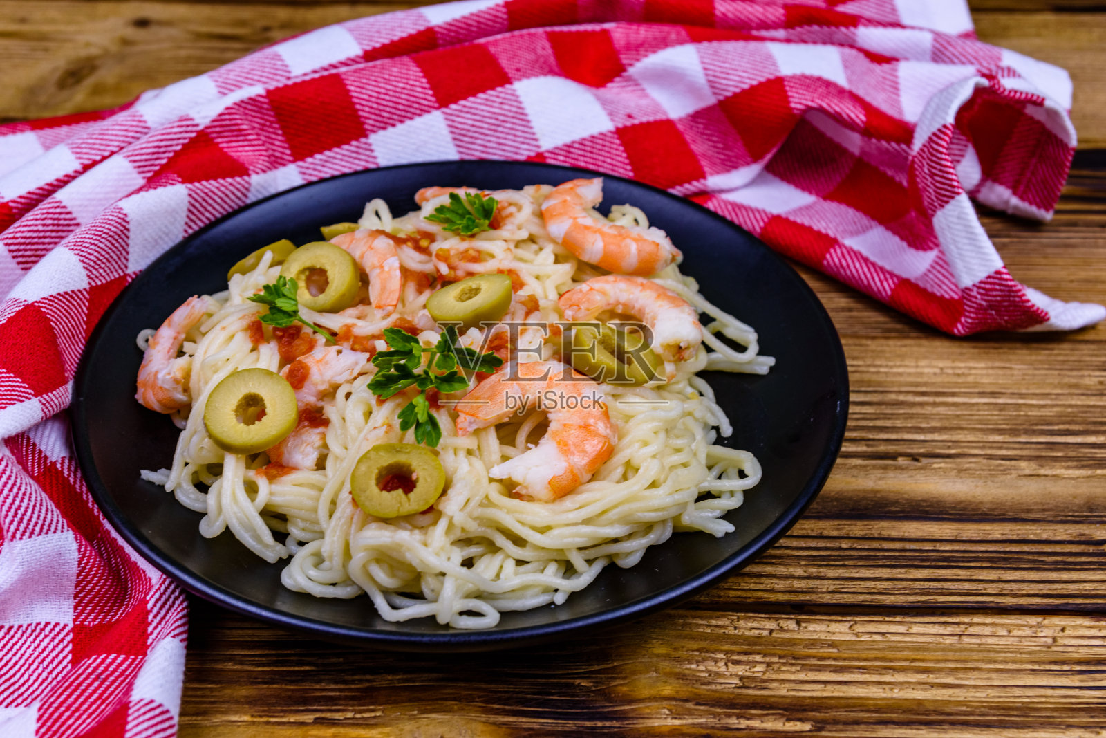 黑色盘子里有虾和橄榄的意大利面食照片摄影图片