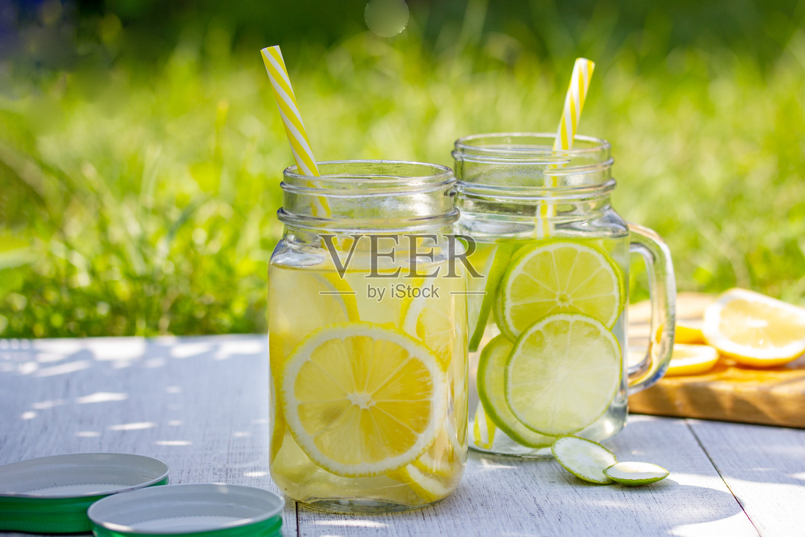 柠檬和酸橙的鸡尾酒被倒进有把手、盖子和管子的罐子里照片摄影图片