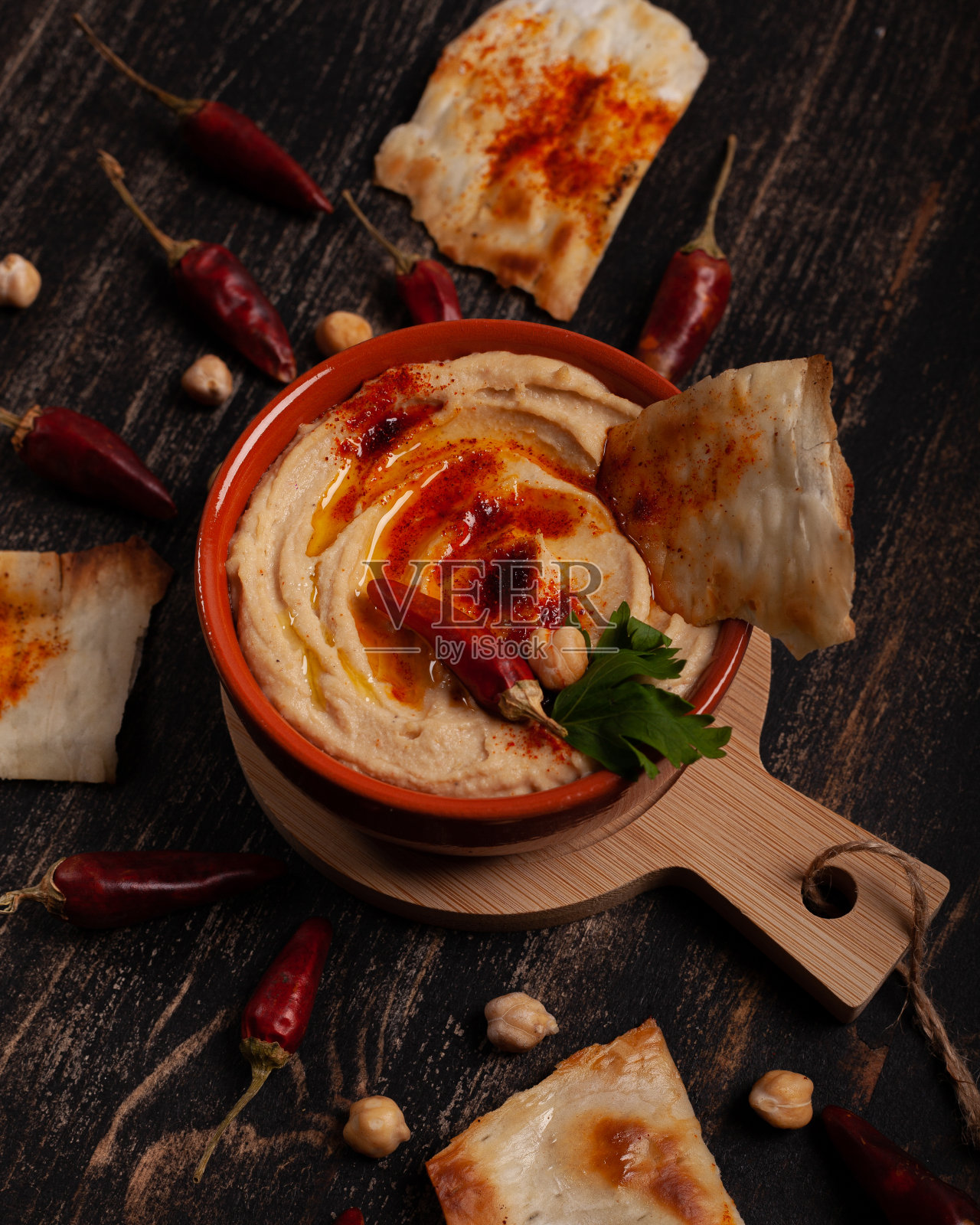 黑色的桌子上放着新鲜的鹰嘴豆泥和辣椒粉照片摄影图片