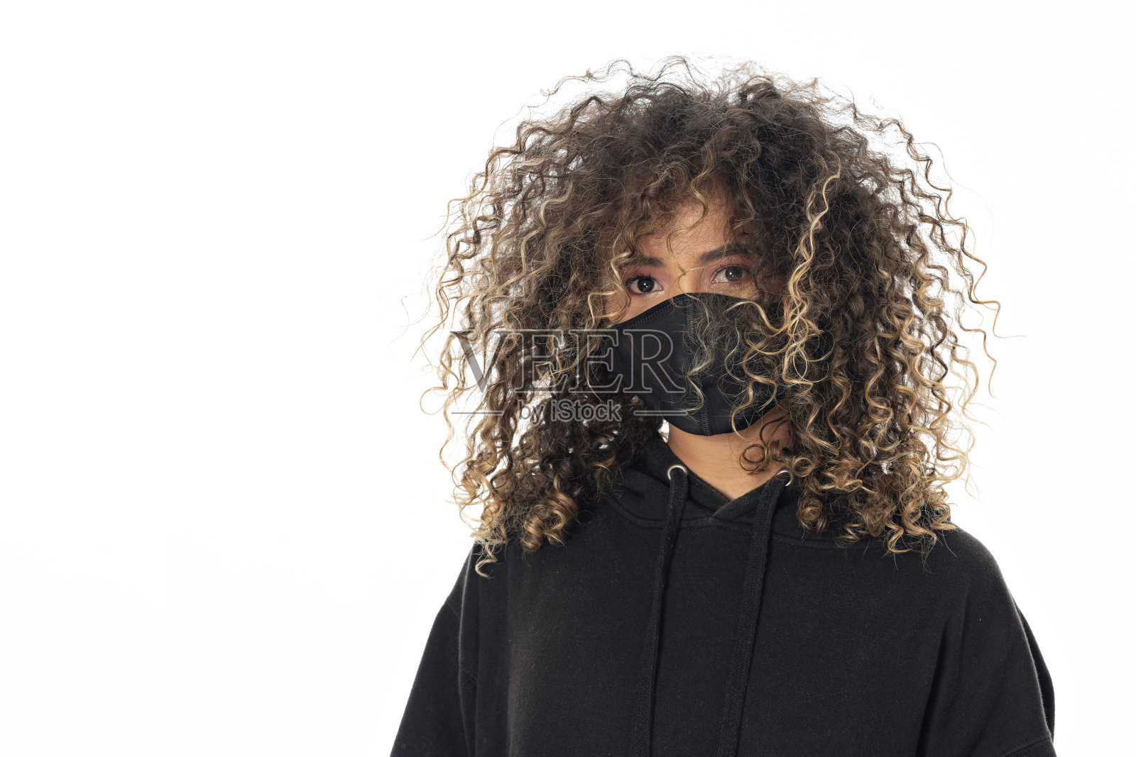 美丽的非裔美国妇女在一个工作室里做肖像,穿着休闲的衣服,戴着面具保护她照片摄影图片