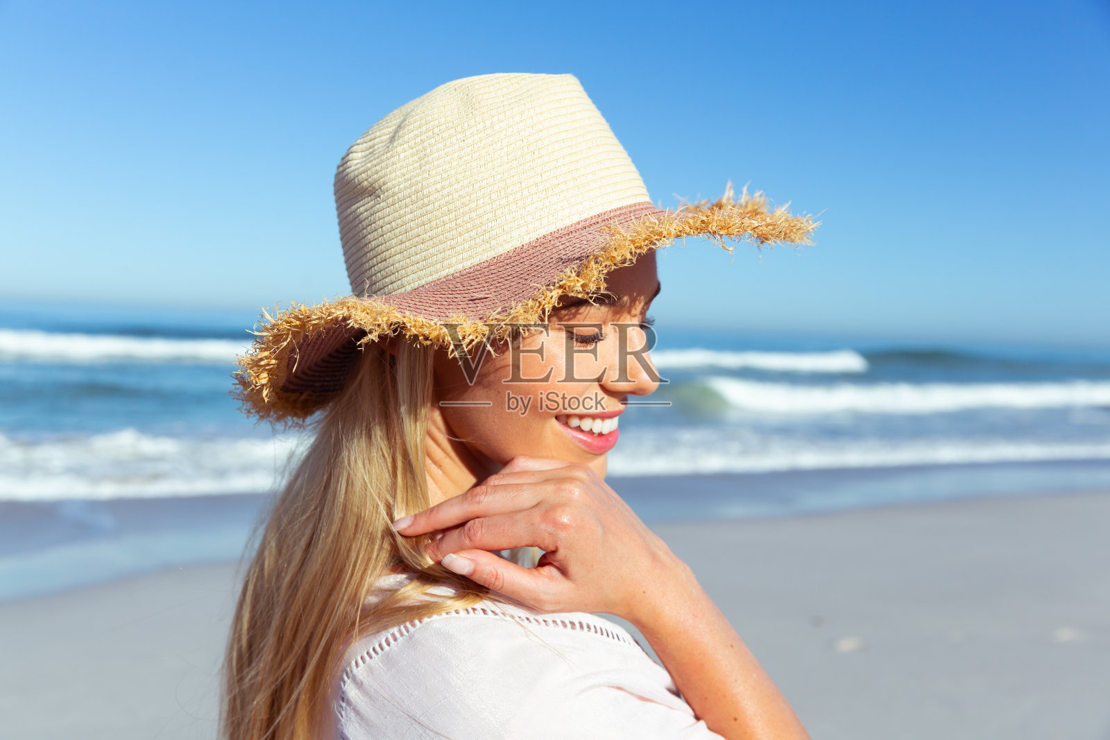 戴着帽子的女人微笑着站在沙滩上照片摄影图片