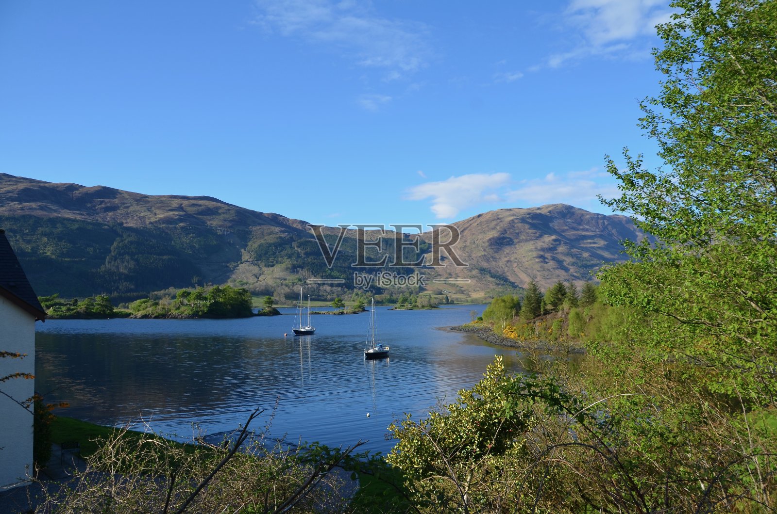 巴拉查利斯湖位于苏格兰高地,背景是帆船和山脉照片摄影图片