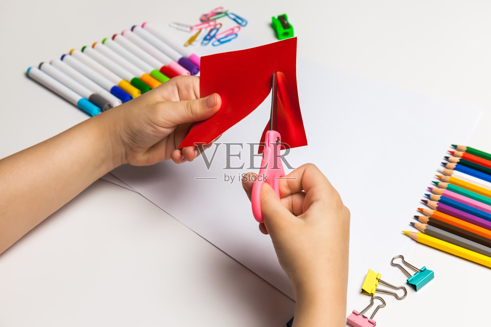 孩子的手在桌子上用剪刀剪彩色纸照片摄影图片