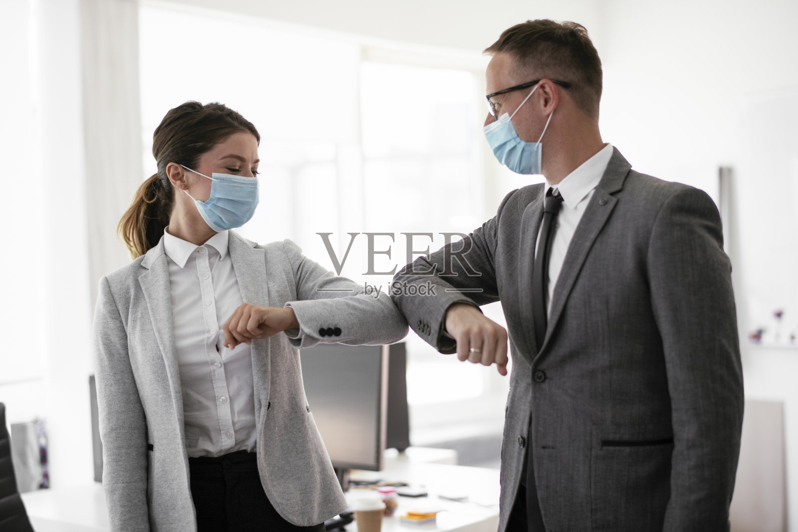 办公室里戴着医用口罩的商人和女商人。照片摄影图片