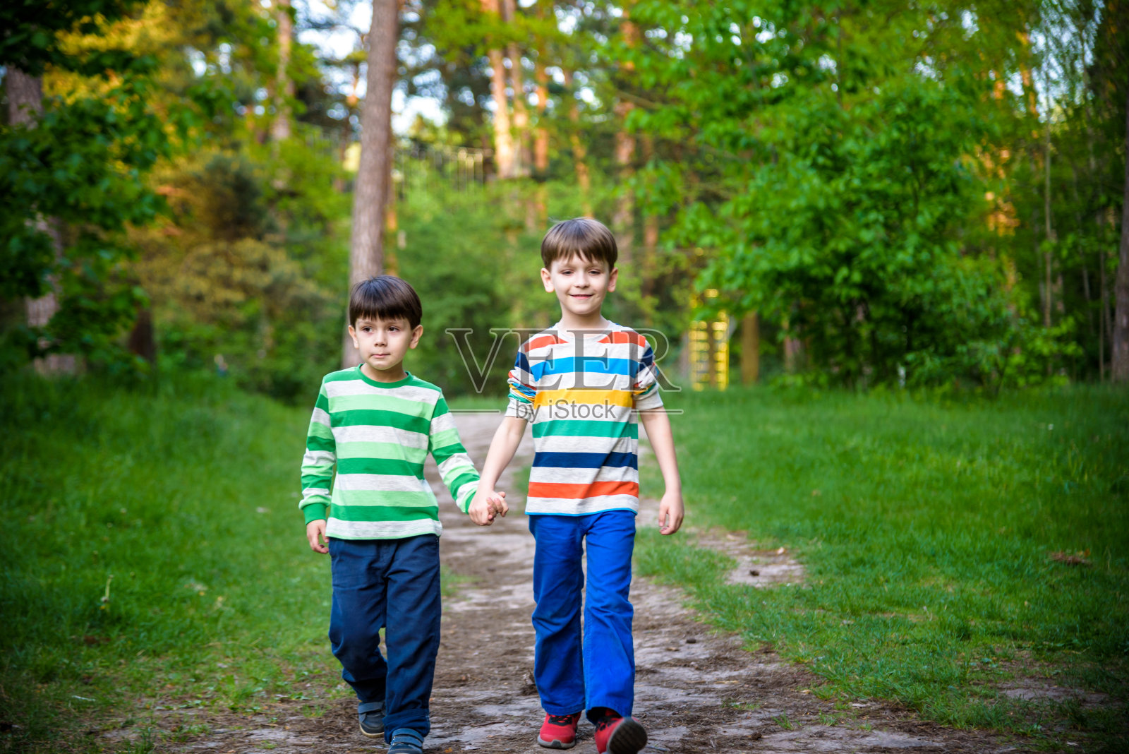 童年,徒步旅行,家庭,友谊和人的概念-两个快乐的孩子走在森林小径照片摄影图片