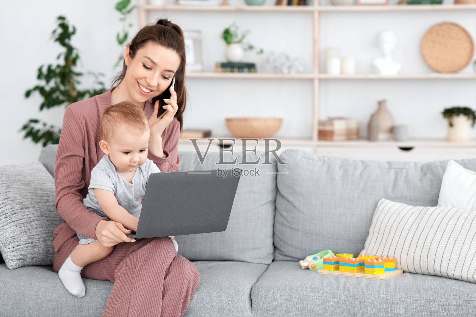 和宝宝一起工作。孩子在笔记本电脑上打字,妈妈在打电话照片摄影图片