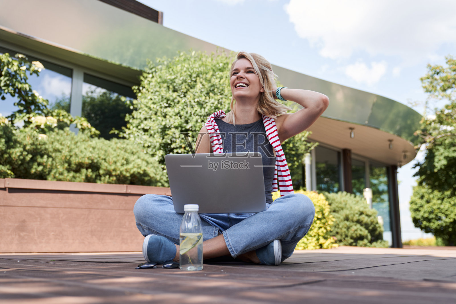 坐在大楼旁边拿着小玩意的乐观女士照片摄影图片