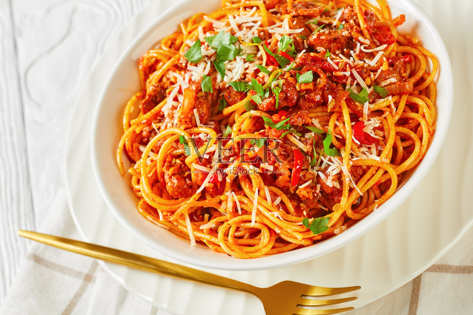 白色碗装意大利面,配猪肉香肠、番茄香料、帕尔玛干酪丝和欧芹碎照片摄影图片