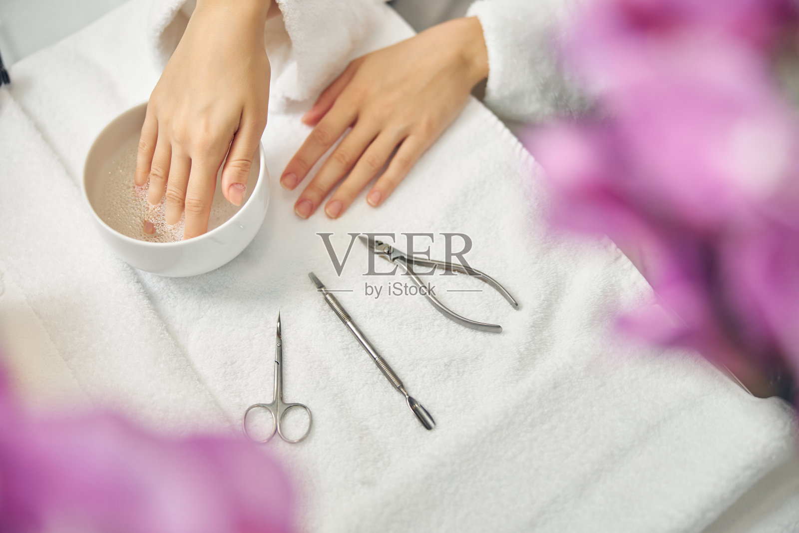 一名女子在粉色鲜花的簇拥下做美甲照片摄影图片