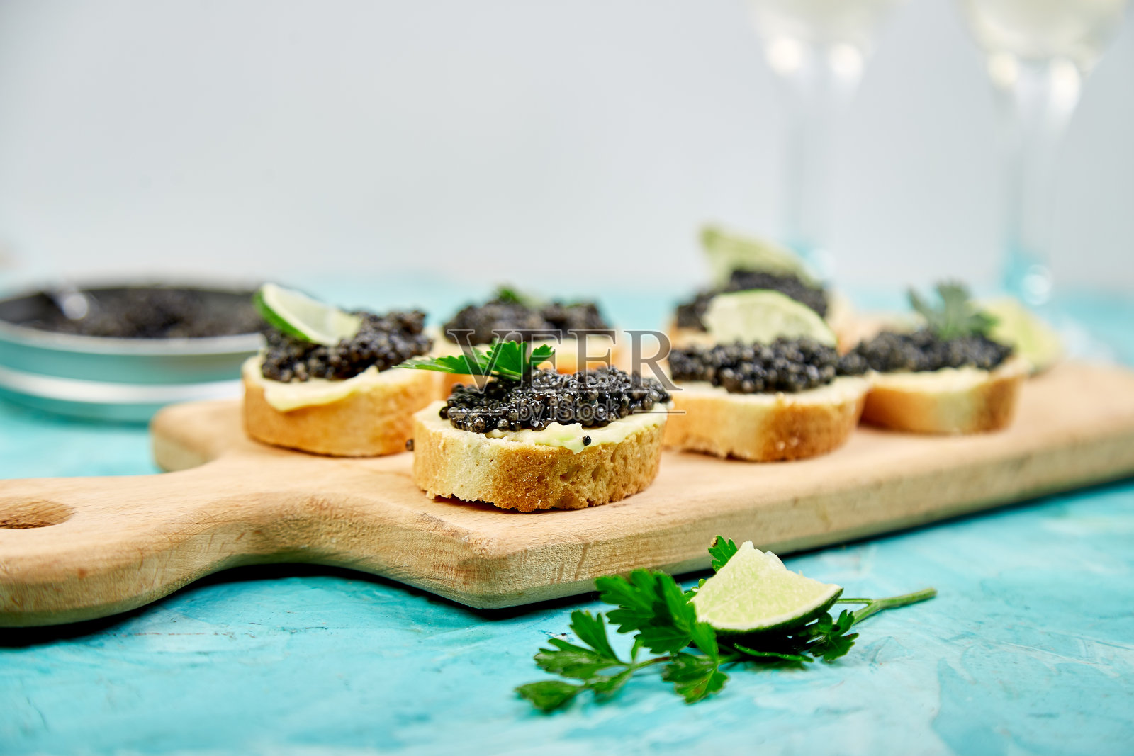 木碗里的鲟鱼黑鱼子酱,白色背景上的三明治和香槟。照片摄影图片