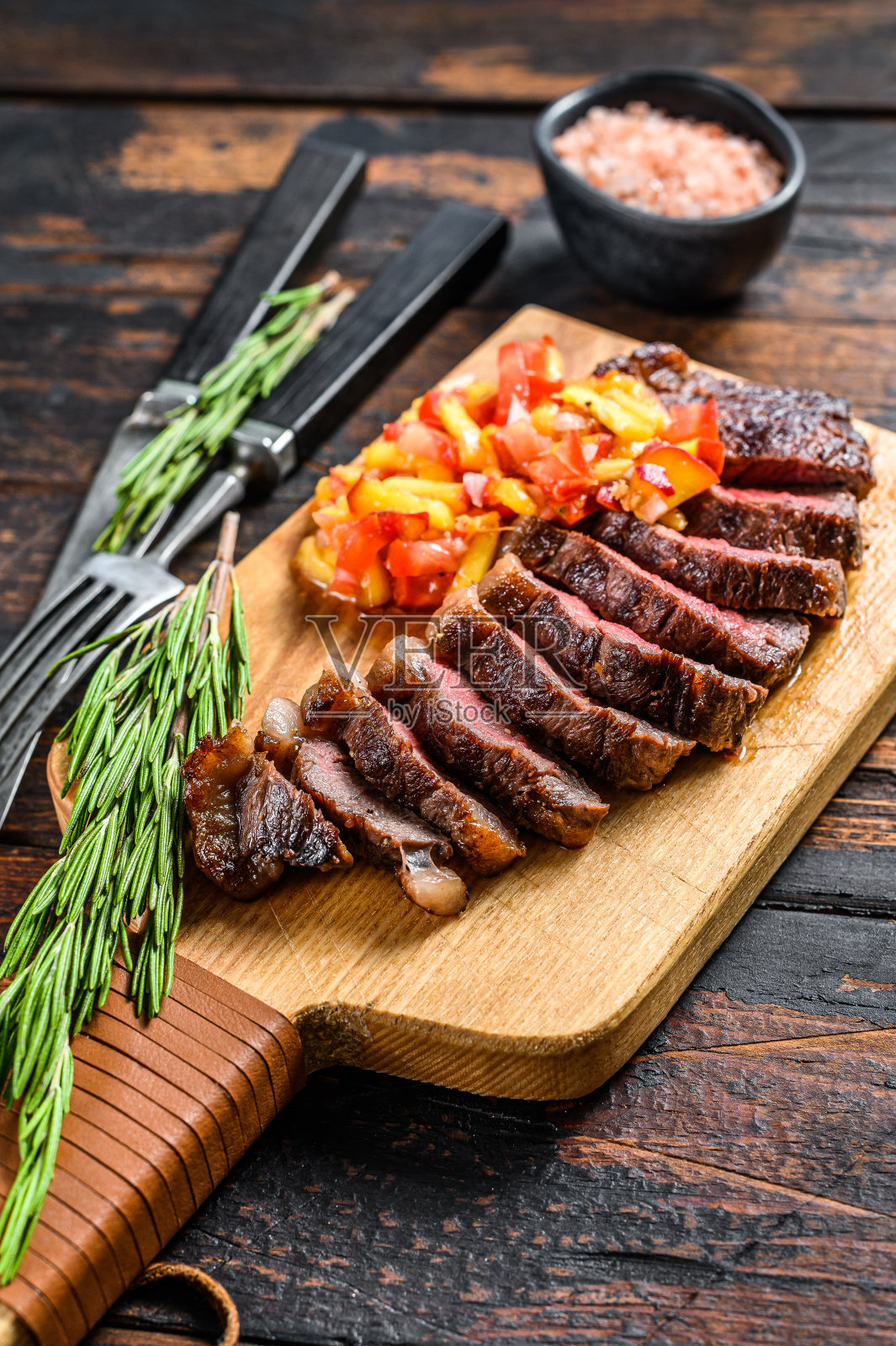 烤上西冷牛排或比坎哈牛排在切板上与香草。深色木制背景。俯视图照片摄影图片