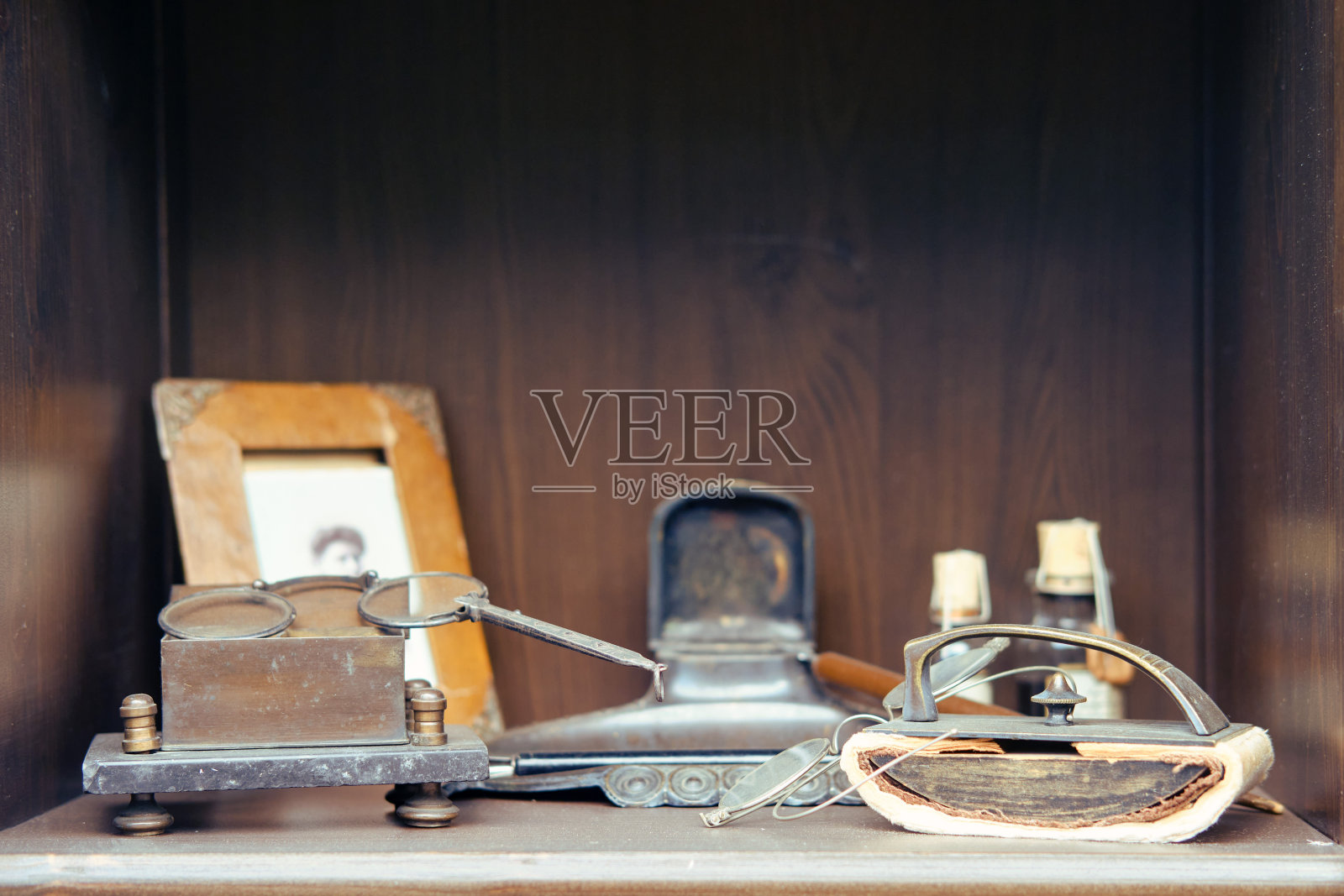 复古邮票,旧照片和药瓶在复古医生桌上。一副眼镜,一件乐器,还有一张老古董桌上的妻子照片照片摄影图片