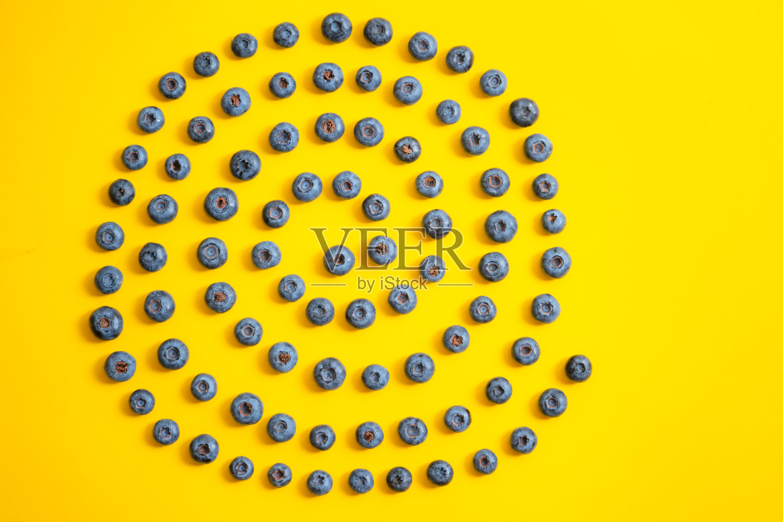 黄色背景上的蓝莓图案。成熟的蓝莓质地更接近了。照片摄影图片