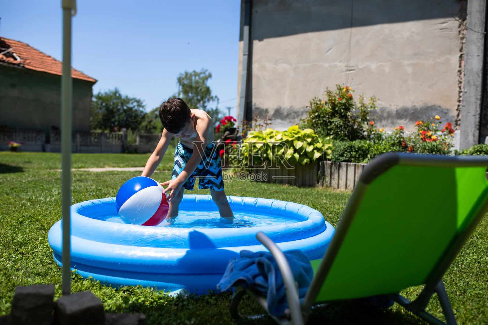 一个男孩在充气游泳池里玩沙滩球照片摄影图片