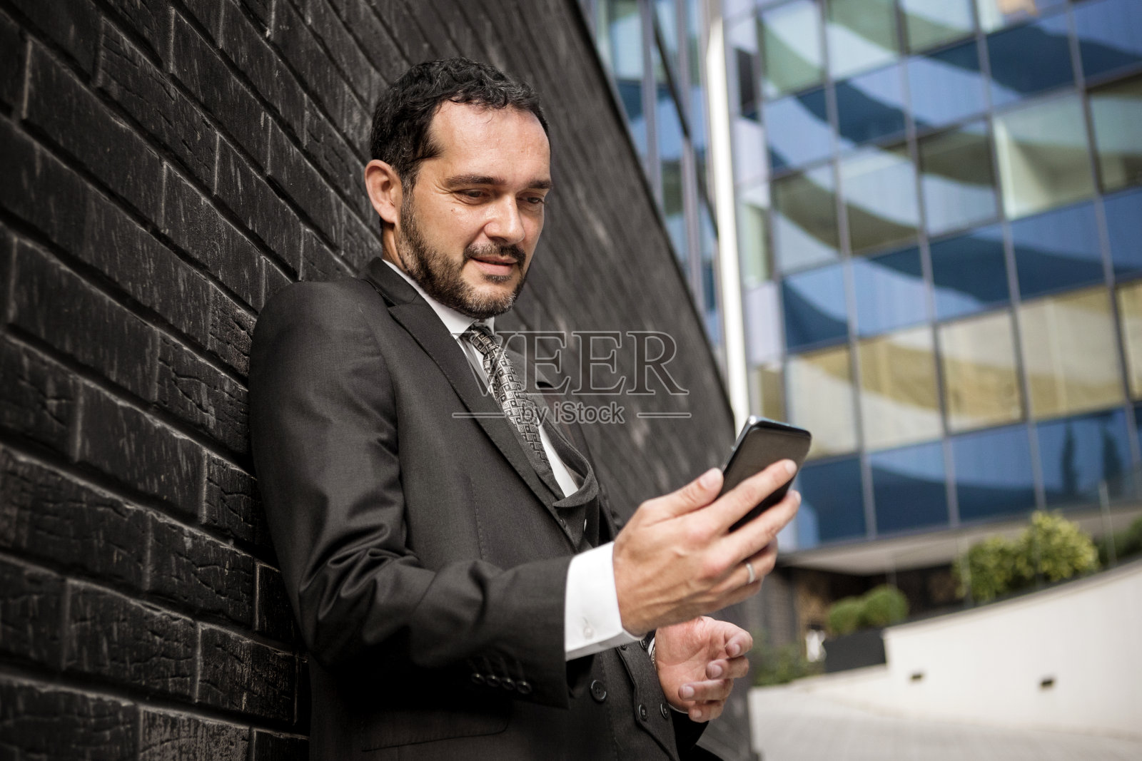 成熟的商人用智能手机查看短信照片摄影图片