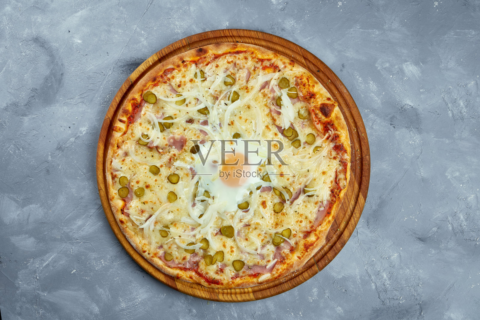 烤制意大利比萨饼配鸡肉。灰色背景的木托盘上放着洋葱、腌黄瓜、意大利腊肠和西红柿。照片摄影图片