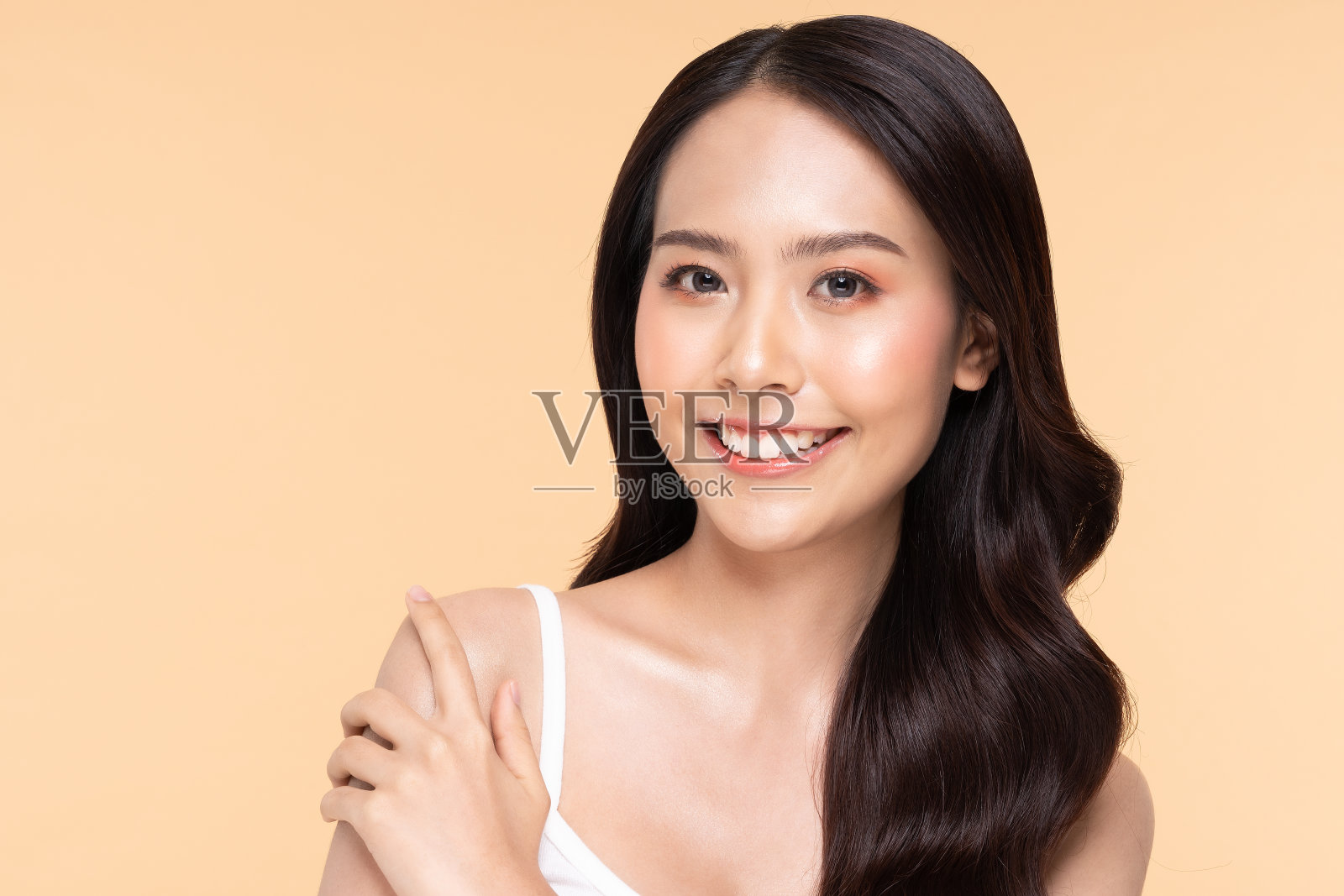 美丽的年轻亚洲女人看着,而触摸肩膀感觉如此快乐和愉快的健康干净和新鲜的皮肤,隔离在米色背景,美丽美容概念照片摄影图片