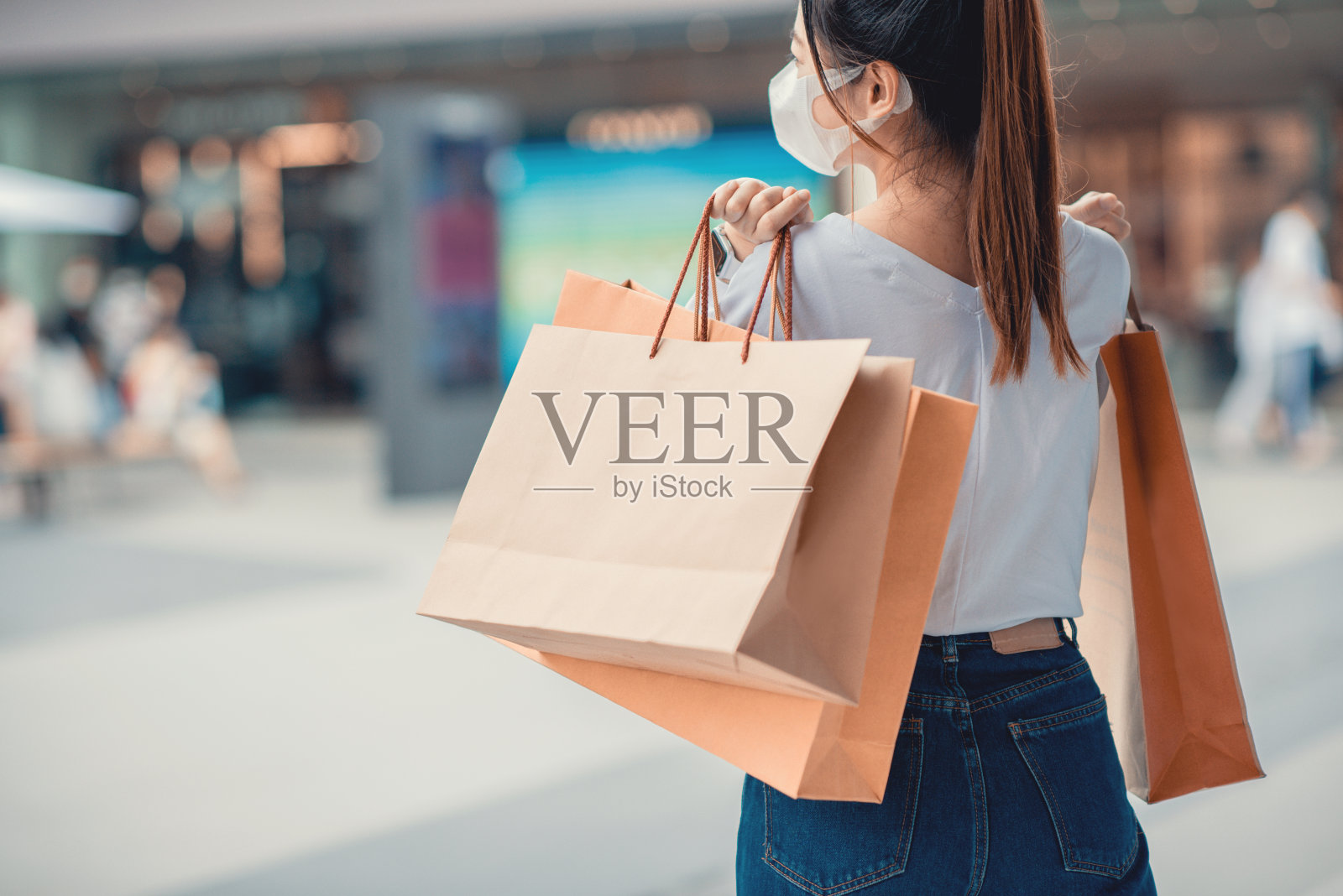 购物期间检疫受孕,快乐女子戴着防护口罩,手持纸袋照片摄影图片