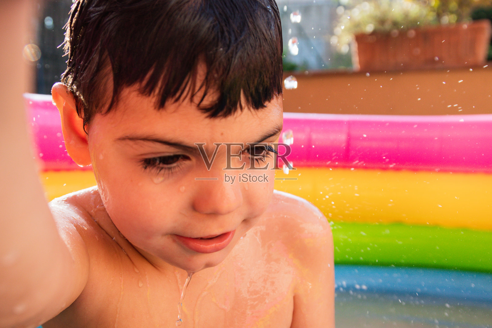 孩子们在外面的彩色塑料泳池里洗澡和玩耍照片摄影图片