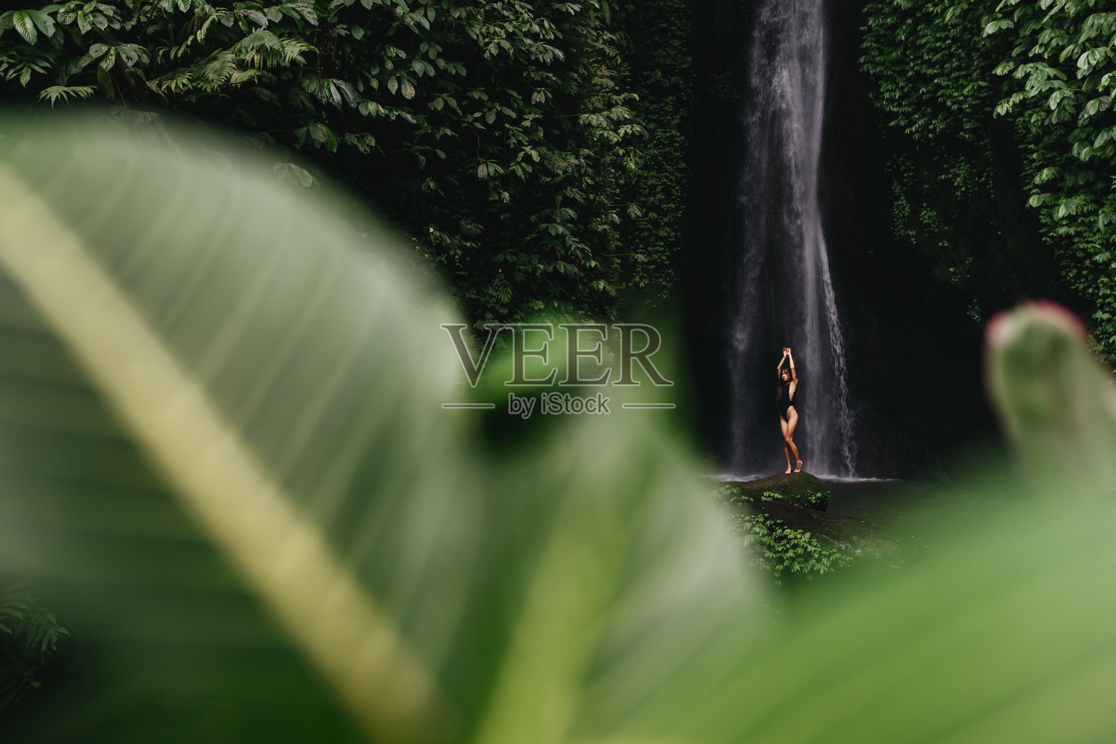 年轻的背包女在看丛林中的瀑布。照片摄影图片