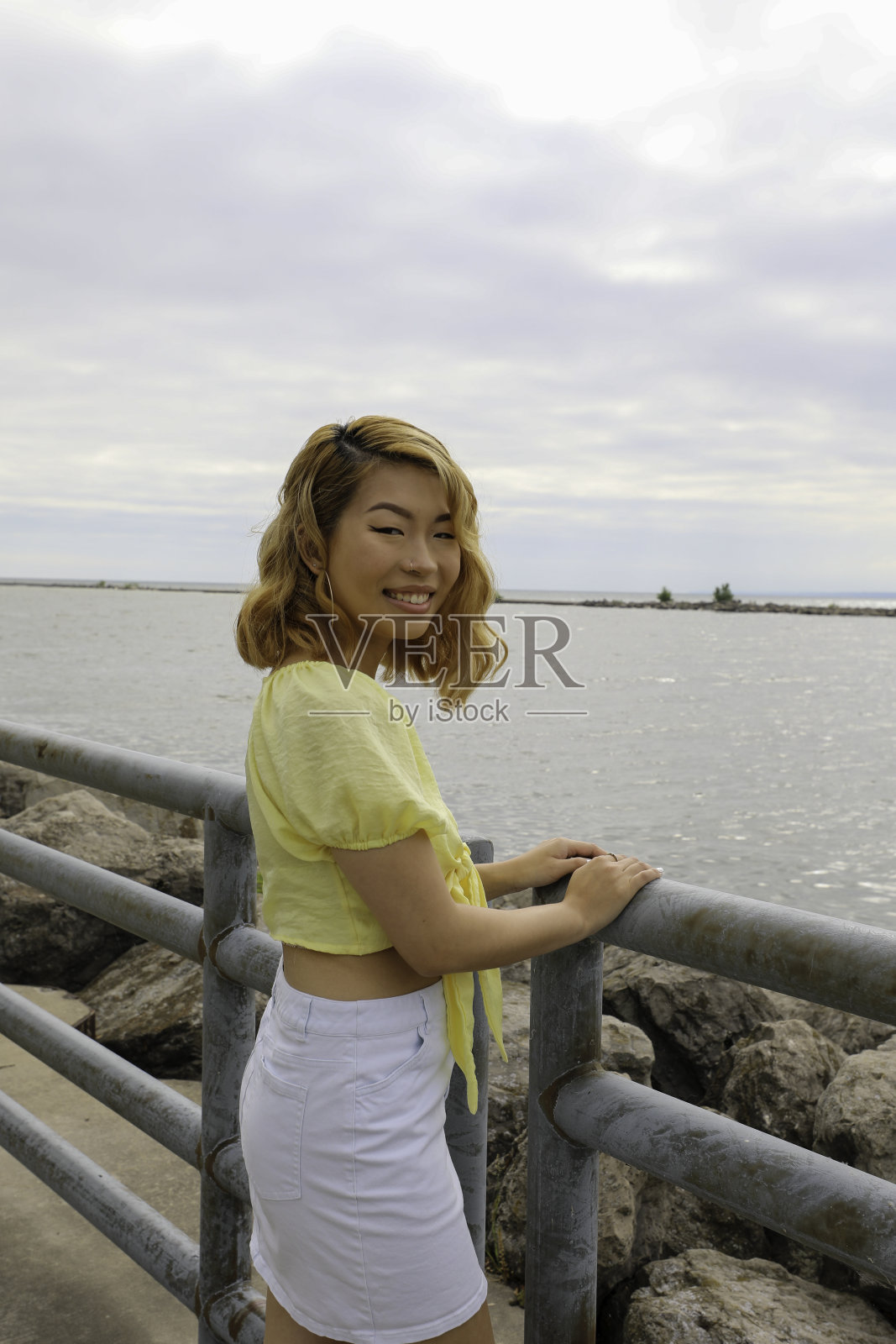 一个夏日的早晨,微笑的年轻女子站在码头上照片摄影图片