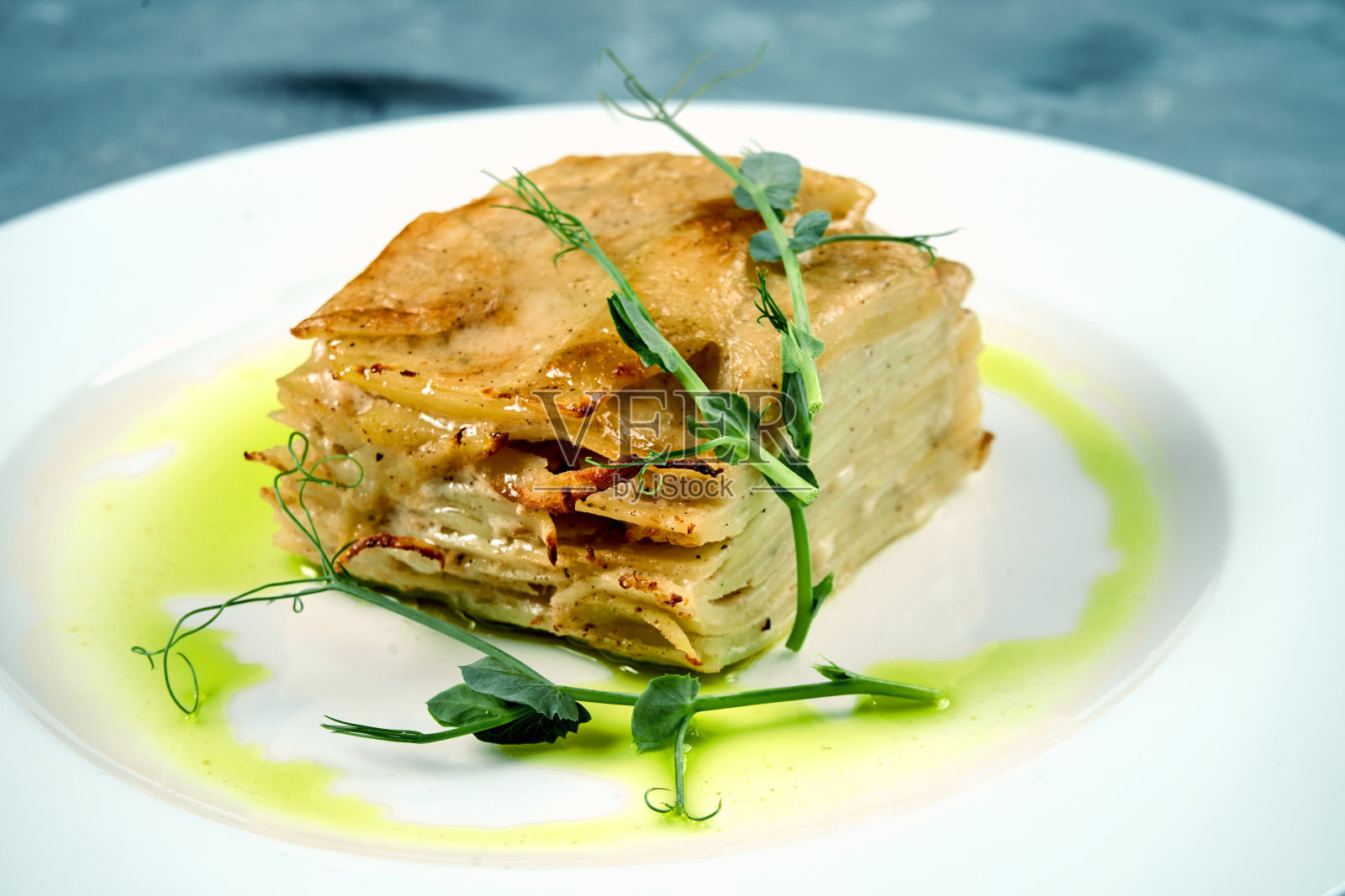 在混凝土背景下的白色盘子里,烤土豆、奶油和奶酪照片摄影图片