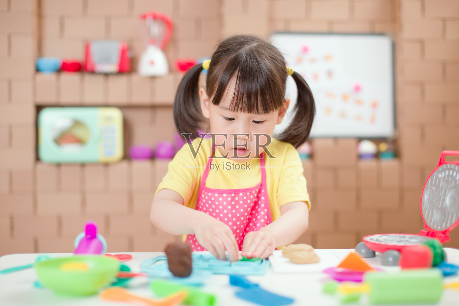 年轻的女孩在厨房里用硬纸板做的东西,为家庭教育制作甜蜜的宝石照片摄影图片