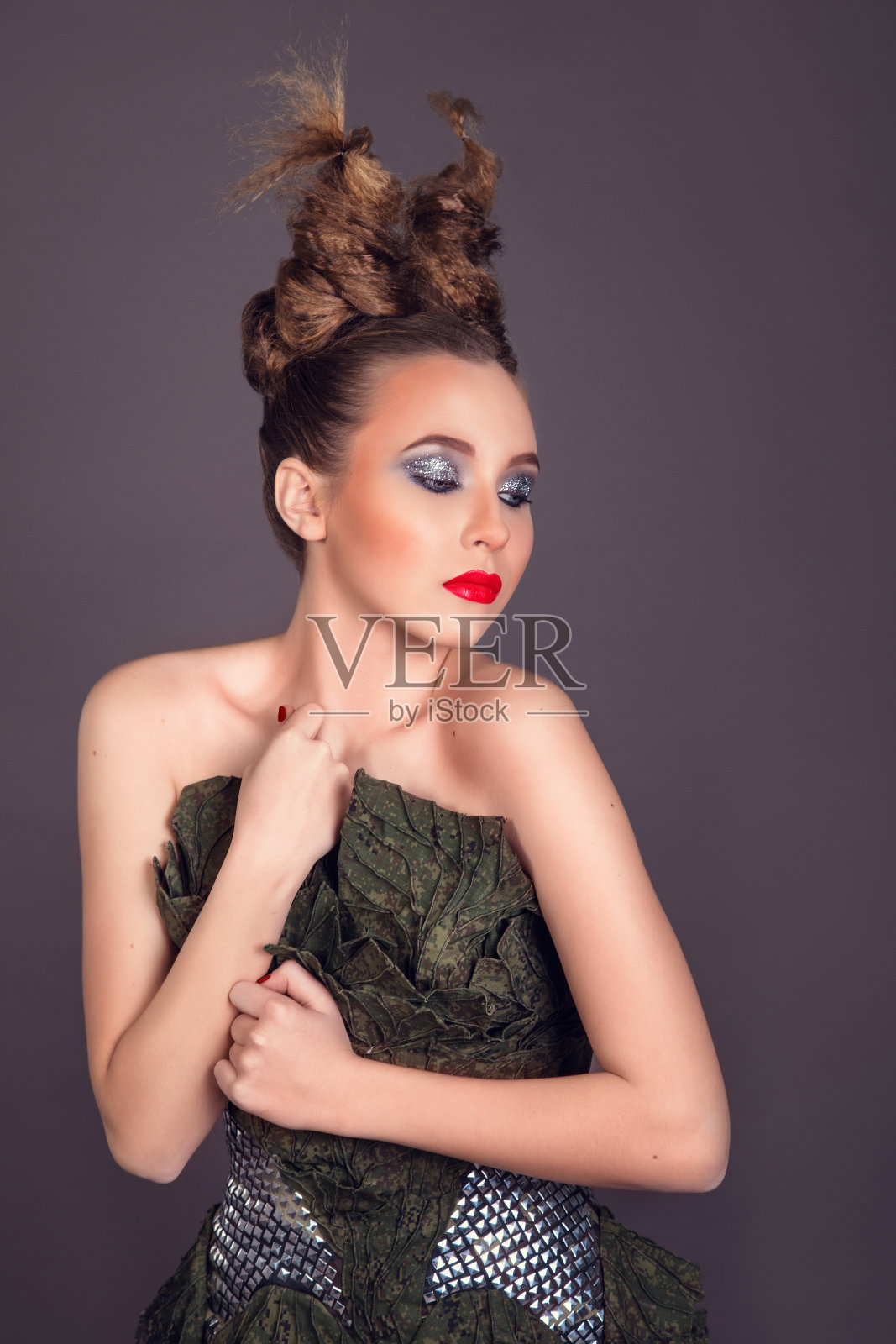 漂亮的金发女人穿着时尚的军装。影棚拍摄。一个有着不寻常的时尚发型和红唇的女孩照片摄影图片