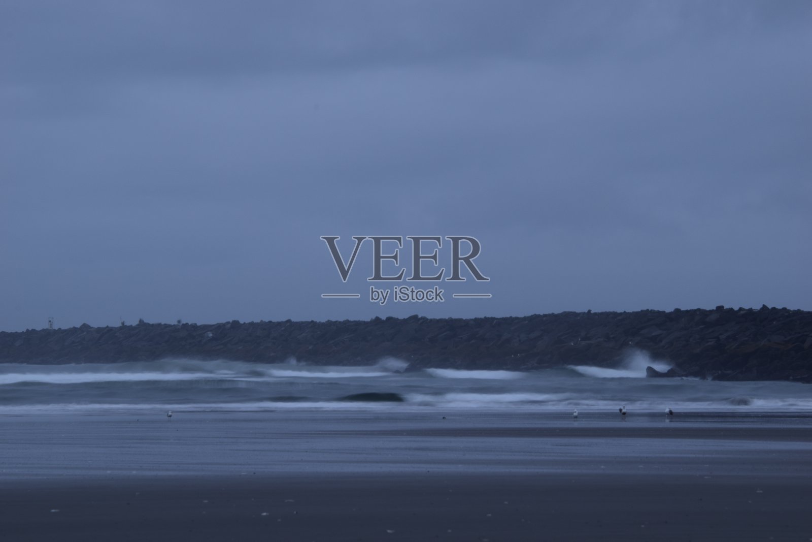 在一个多云的日出期间,码头在波涛汹涌的海面上驶出照片摄影图片