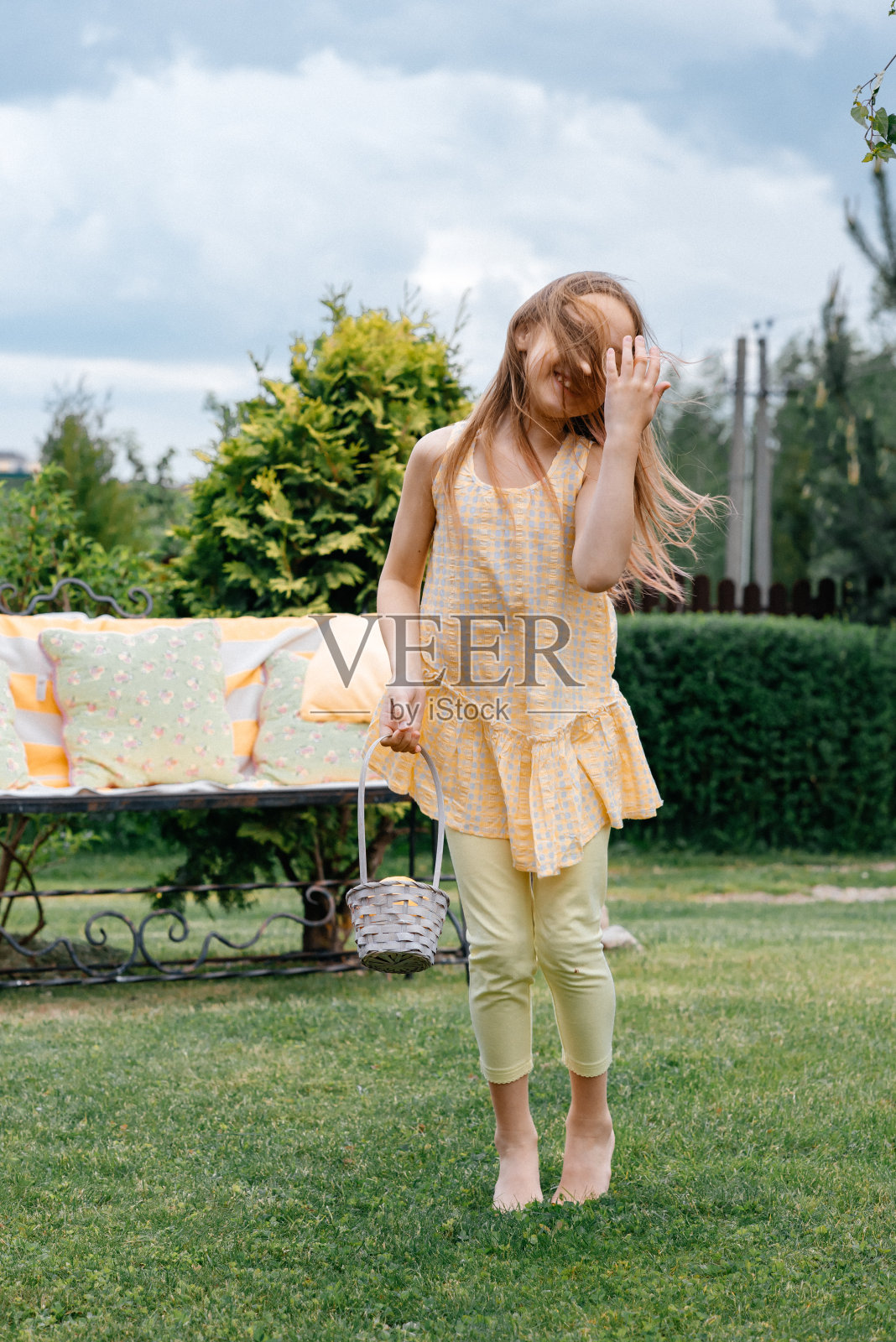 快乐的黑发女孩在草地上跳黄色的裙子。夏天阳光灿烂的日子。照片摄影图片