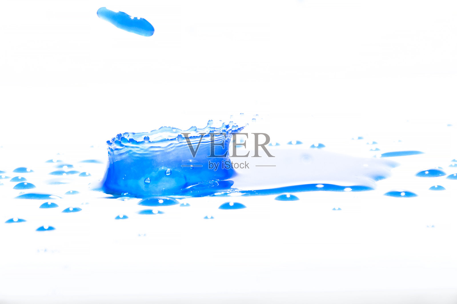 蓝色的水溅在白色的背景上,照片摄影图片