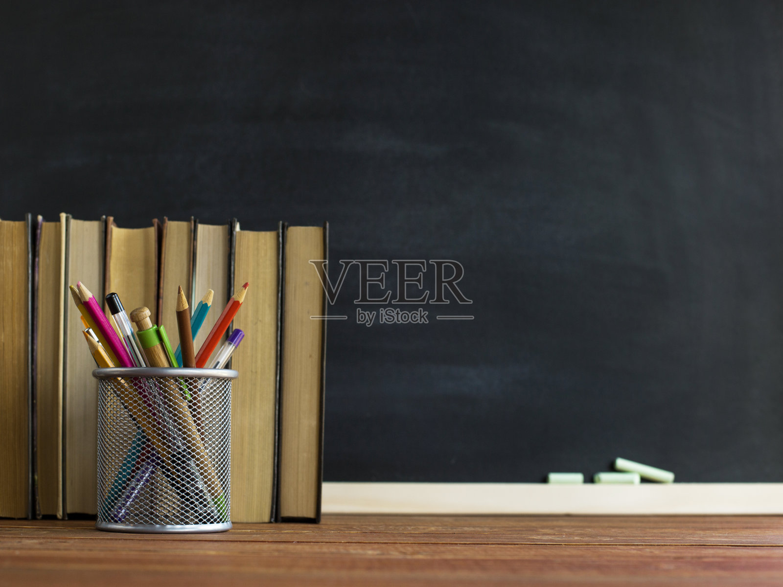 课本和学习用品放在桌子上,背靠黑板以粉笔作背景。学校的概念与copyspase。照片摄影图片