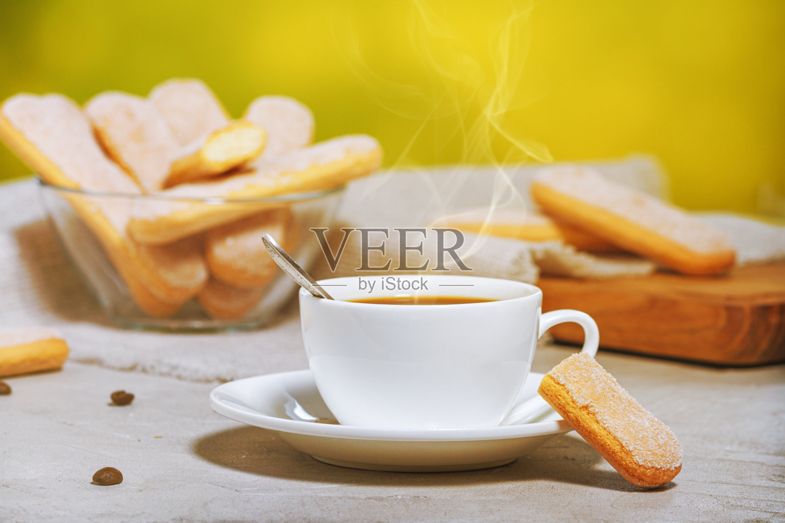 白色的热咖啡与蒸汽,传统的意大利savoiardi饼干或手指饼干盘子和玻璃碗。有选择性的重点照片摄影图片