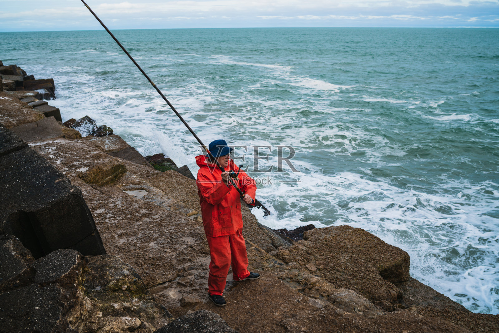 老人在海里钓鱼。照片摄影图片