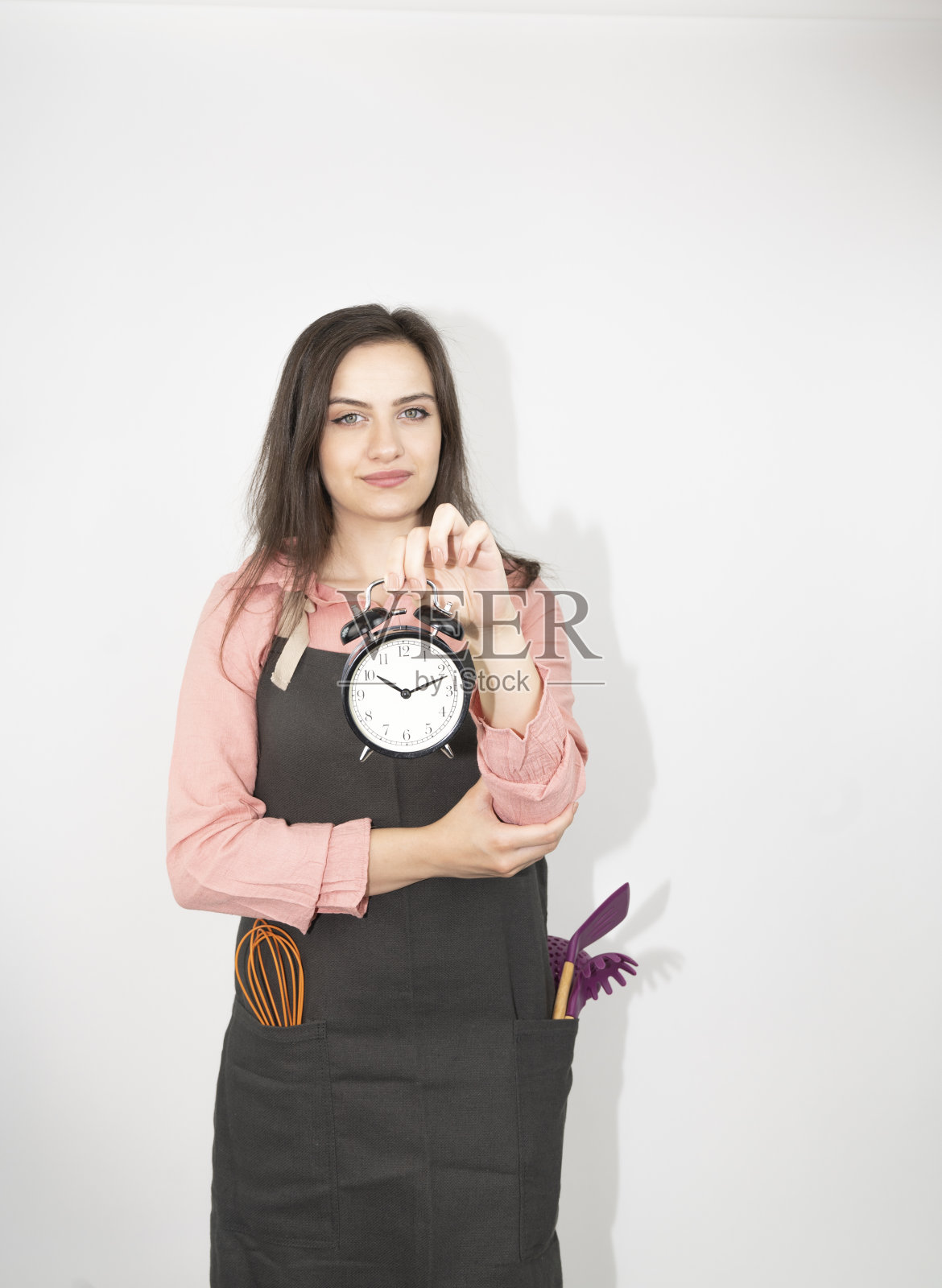 家庭主妇女厨师或面包师系着黑色围裙,厨师帽孤立在白色背景上。24、手里牵着微笑的女人round clock快点。模拟复制空间的概念照片摄影图片