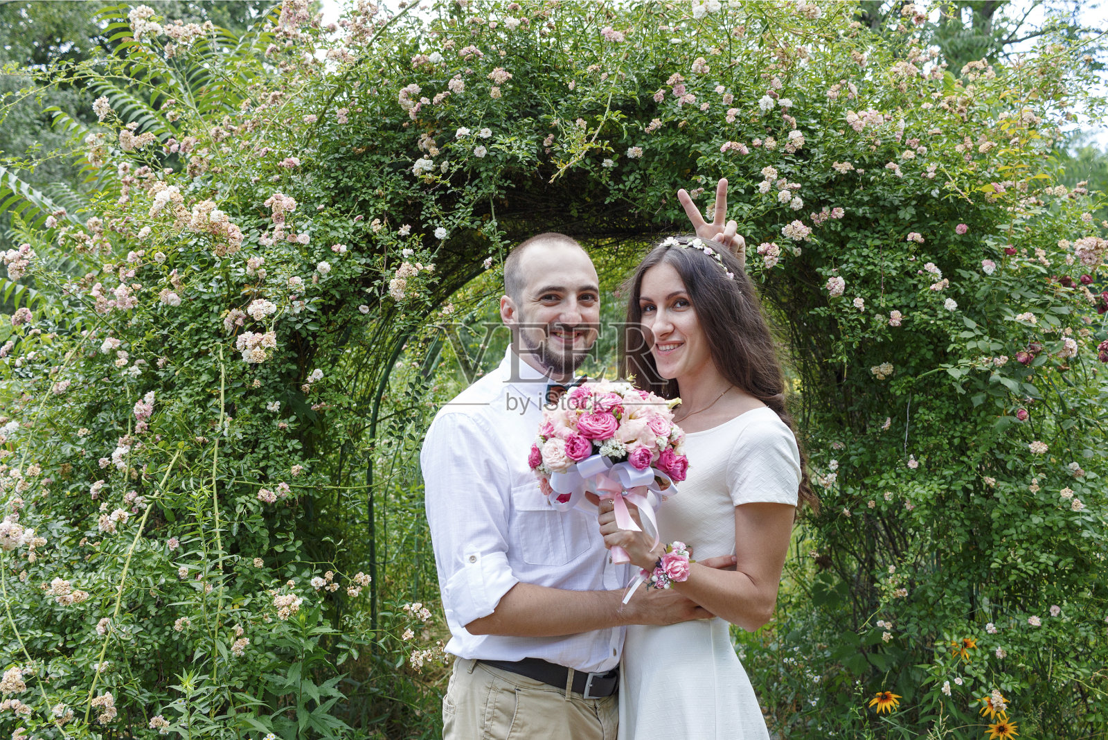 情人新婚夫妇。一对相爱的漂亮夫妇。一对恩爱的情侣在花园的花丛中。就结婚了。美丽的新娘和新郎在公园里拥抱。新婚夫妇的婚纱照照片摄影图片