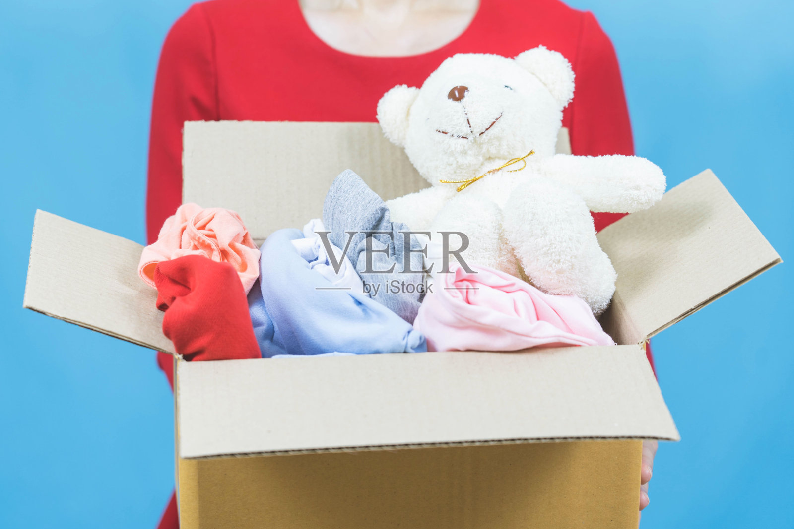 捐赠的概念。女人拿着一个捐赠箱,里面装满了衣服和娃娃,选择性聚焦照片摄影图片